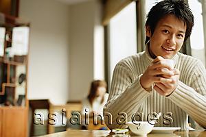 Asia Images Group - Young man sitting at table holding teacup