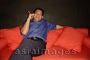 Asia Images Group - Man with cigar, lounging on sofa