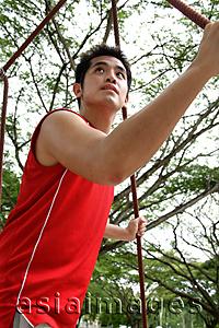 Asia Images Group - Man holding on to rope on a jungle gym, low angle view