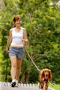 Asia Images Group - Young woman walking her dog