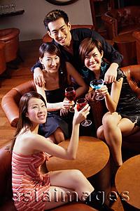 Asia Images Group - Three young women and a man in entertainment club, looking at camera