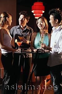 Asia Images Group - Young adults in night club, standing and holding drinks
