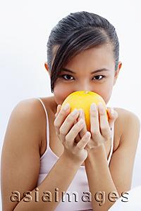Asia Images Group - Woman holding orange to face