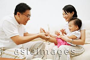 Asia Images Group - Family with one child sitting face to face, father holding daughter's leg