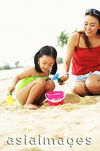 Asia Images Group - Mother with daughter on beach, playing with sand