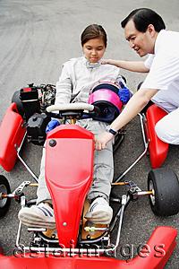 Asia Images Group - Young woman in go-cart, father crouching down next to her