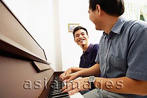 Asia Images Group - Father and son playing piano, side by side, looking at each other