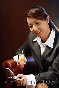 Asia Images Group - Woman holding glass of champagne and mobile phone, text messaging