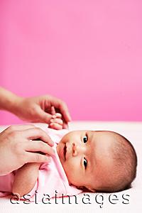 Asia Images Group - Baby lying down, looking at camera, mother holding her hand
