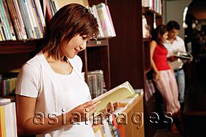 Asia Images Group - Young woman at bookstore, looking at book