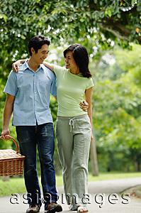 Asia Images Group - Couple walking in park, man carrying picnic basket