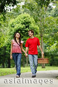 Asia Images Group - Couple holding hands and walking in park , man carrying picnic basket