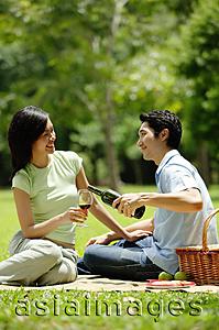 Asia Images Group - Couple in park, man pouring wine for woman