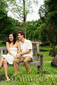 Asia Images Group - Couple sitting on park bench, woman laughing