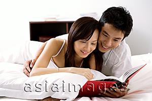 Asia Images Group - Couple lying on bed, reading book