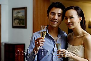 Asia Images Group - Couple holding champagne glasses, smiling at camera