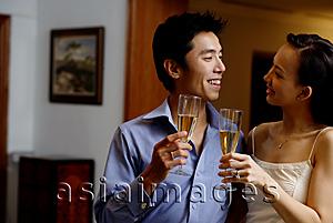 Asia Images Group - Couple standing face to face, holding champagne glasses