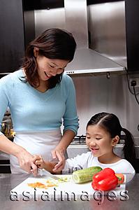 Asia Images Group - Mother cutting vegetables, daughter helping her