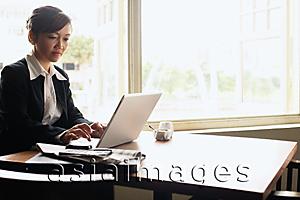 Asia Images Group - Businesswoman at table, using laptop