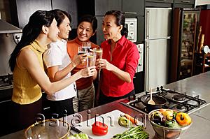 Asia Images Group - Women in kitchen, holding wine glasses, toasting