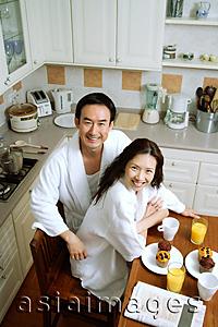 Asia Images Group - Couple sitting in kitchen, smiling at camera, high angle view
