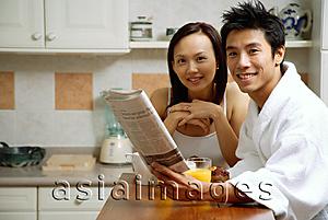 Asia Images Group - Couple in kitchen, man holding newspaper, smiling at camera