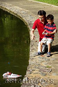 Asia Images Group - Father and son playing with remote control boat