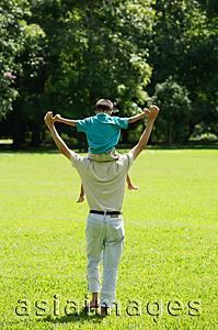 Asia Images Group - Father carrying son on shoulders, walking in field
