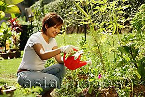 Asia Images Group - Woman watering plants in garden