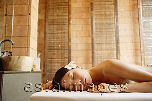 Asia Images Group - Woman lying on massage table, eyes closed, wearing flowers