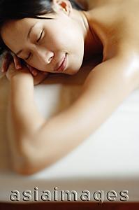 Asia Images Group - Young woman lying on front, eyes closed