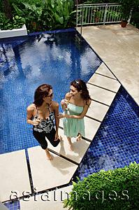 Asia Images Group - Two women standing next to swimming pool, talking