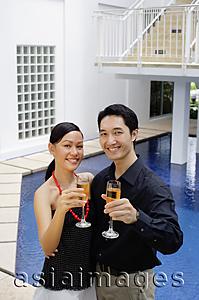 Asia Images Group - Couple by poolside, holding up champagne glasses towards camera