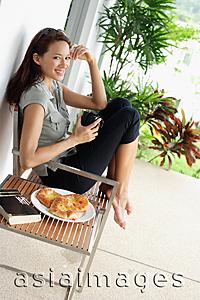 Asia Images Group - Woman having coffee on patio, hand on head, smiling at camera