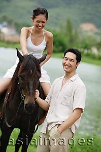 Asia Images Group - Woman sitting on horse, man standing holding reins