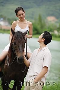 Asia Images Group - Woman sitting on horse, man standing holding reins looking at her