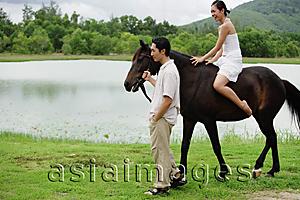 Asia Images Group - Woman riding on horse, man holding reins walking beside her
