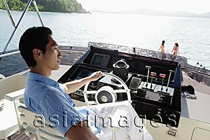 Asia Images Group - Man sitting at helm of yacht, looking away