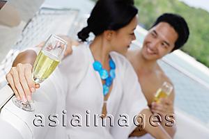 Asia Images Group - Couple sitting side by side on yacht holding champagne glasses