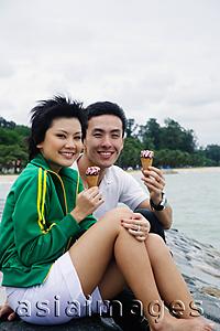 Asia Images Group - Couple sitting on breakwater, eating ice cream