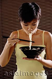 Asia Images Group - Young woman eating a bowl of noodles