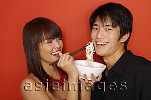 Asia Images Group - Young woman feeding man with noodles