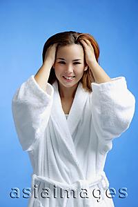 Asia Images Group - Young woman wearing white bathrobe, hands in hair
