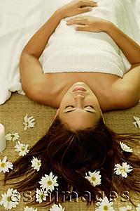 Asia Images Group - Young woman lying on back, flowers scattered around her