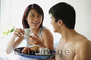 Asia Images Group - Couple having breakfast in bed, man holding tray, woman with cup and saucer
