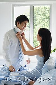 Asia Images Group - Couple in bedroom, woman adjusting man's tie