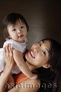 Asia Images Group - Mother carrying young daughter, smiling at camera