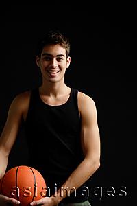 Asia Images Group - Man standing with basketball, smiling at camera