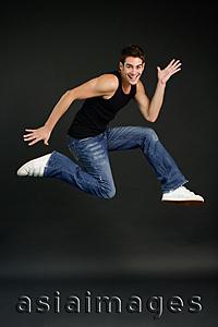 Asia Images Group - Man jumping in mid air, smiling at camera