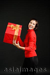 Asia Images Group - Woman in red turtleneck carrying big red box with gold ribbon